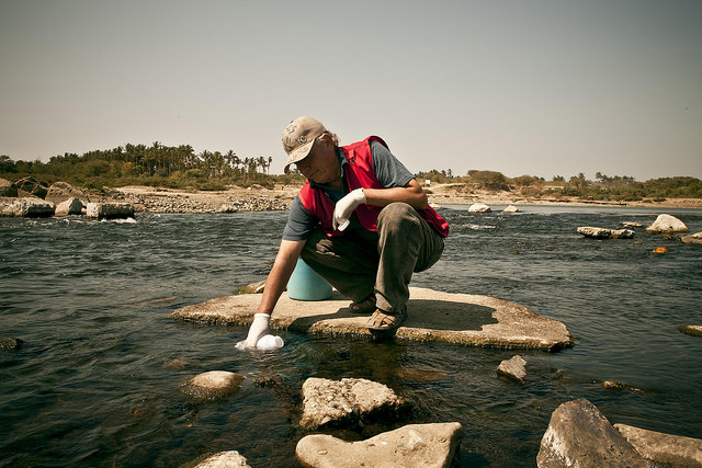 Hombre extrayendo una muestra de un río